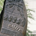 Große Kaffeebohne, Denkmal auf der »Coffee Plaza« Sandtorpark, gestiftet 2009 durch die »Neumann Kaffee Gruppe«.
Die »Neumann Kaffee Gruppe« mit einem Umsatz von 2,4 Mrd. USD und Sitz in der Hafencity Hamburg, hat 2001 ihre Plantage in Mubende/Uganda nach der Vertreibung von 2000 Menschen durch das ugandische Militär erworben. Skulpur auf der »Coffee Plaza«